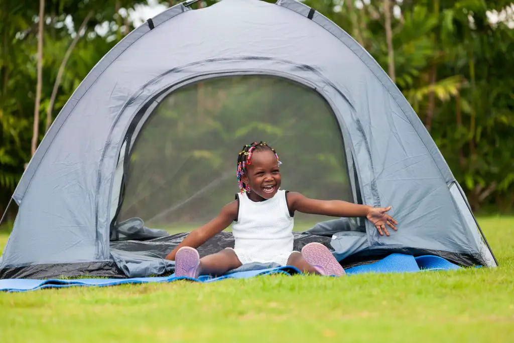 Toddler sitting in front of tent