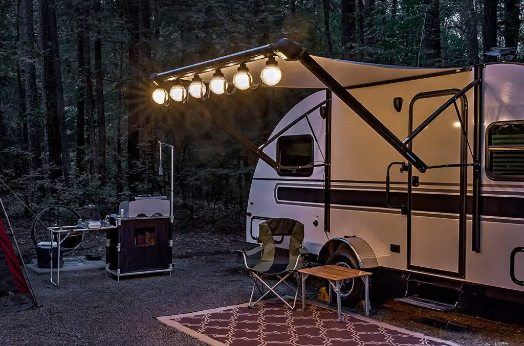 Camper in the forest with large round RV awning lights