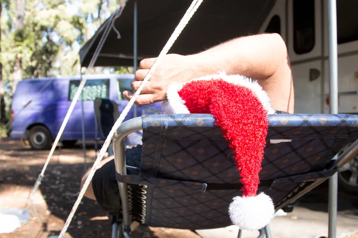 Person wearing a santa hat lying on a chair at a campsite