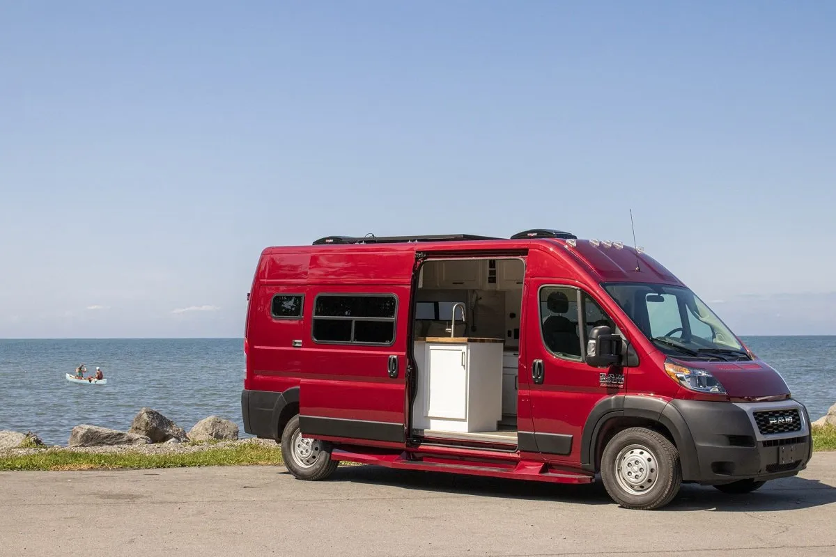 red campervan parked beside the ocean